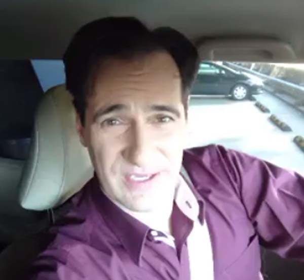 Carl Azuz poses for a picture inside his car.